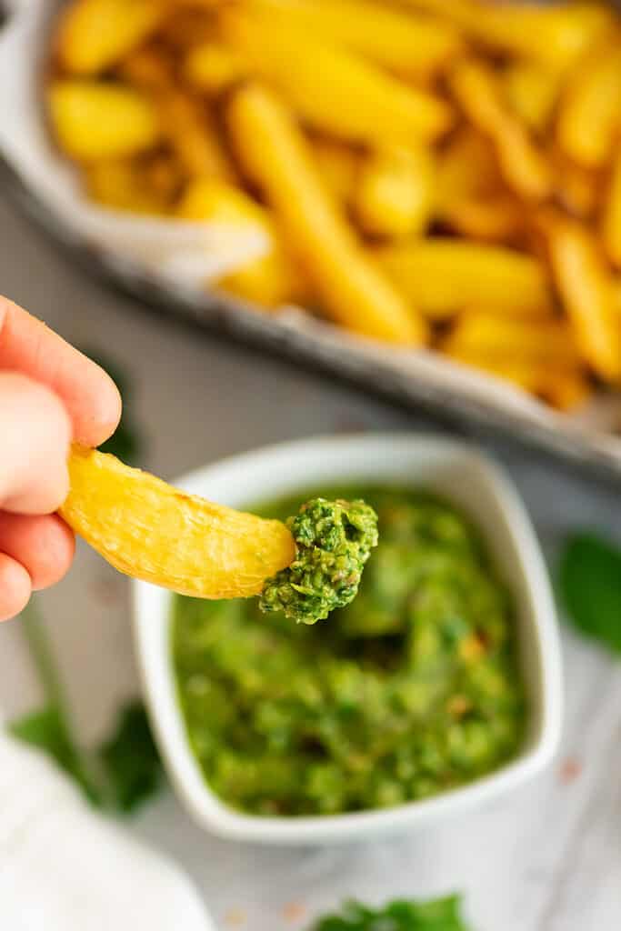 Fry being dipped in cilantro chimichurri sauce.