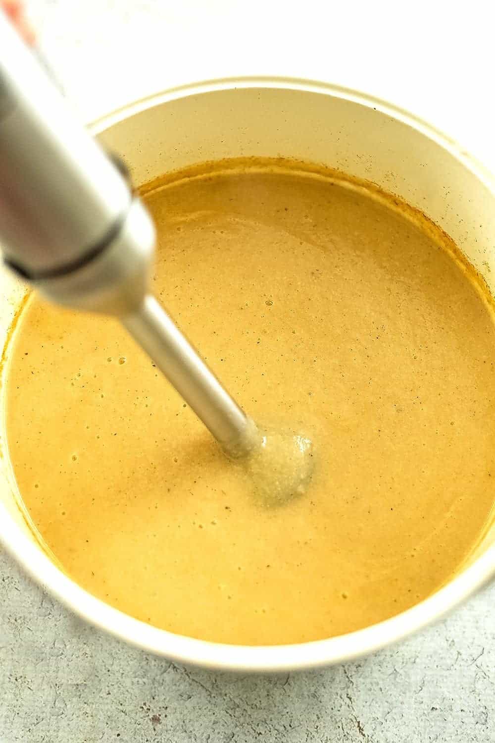 Immersion blender blending up the soup after cooking.