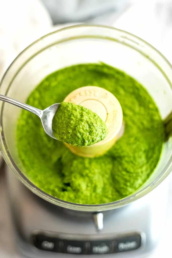Spoon scooping out a serving of white bean pesto from food processor.