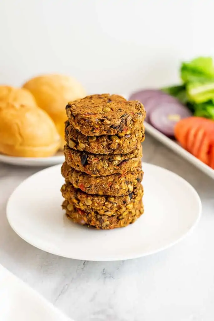 Black bean lentil burgers stacked on a white plate.