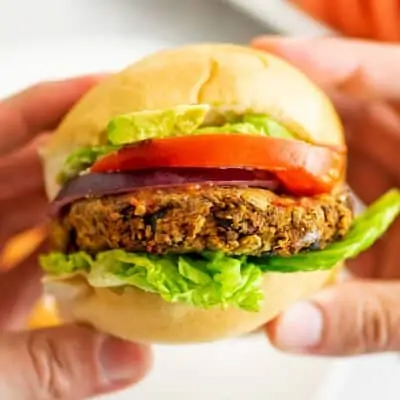 Hands holding a black bean lentil burger.