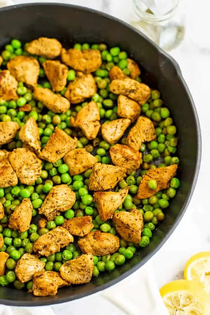 Peas and chicken in a cast iron skillet.
