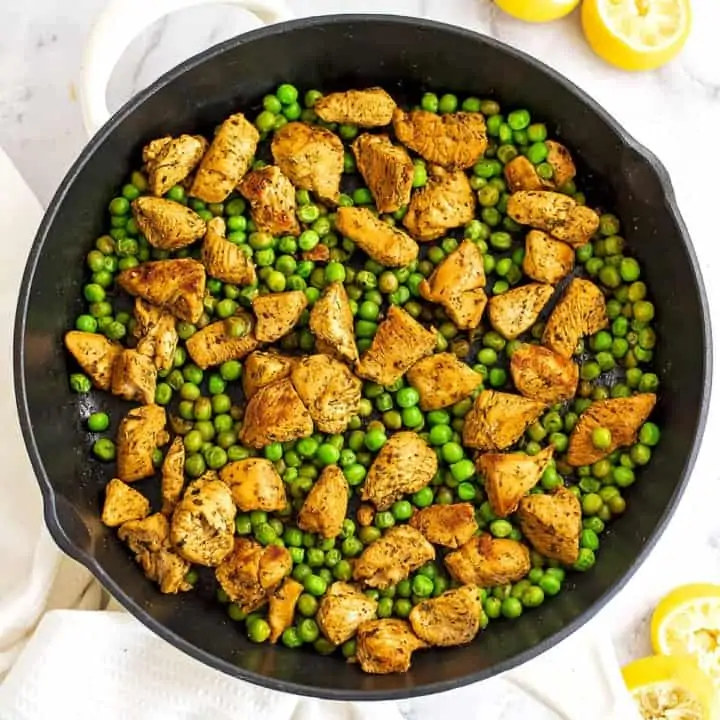 Cast iron skillet filled with chicken and peas.