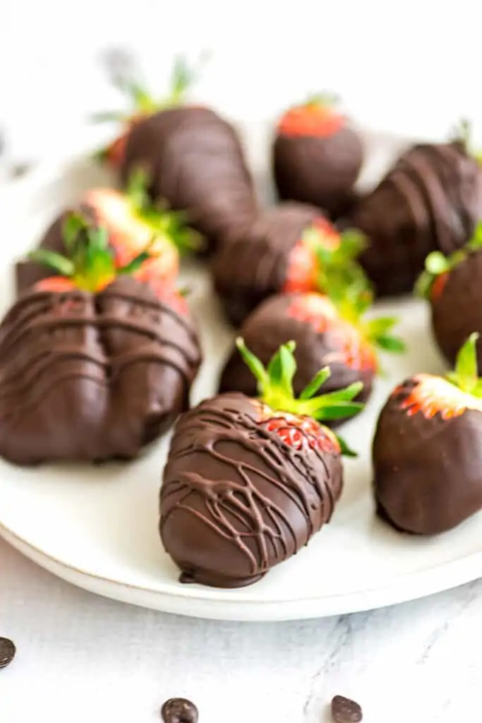 Chocolate covered strawberries on a white plate.