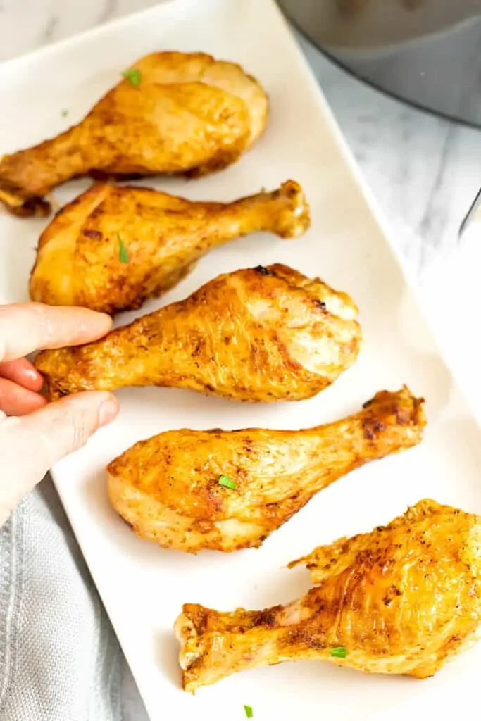 Hand holding a single chicken drumsticks.