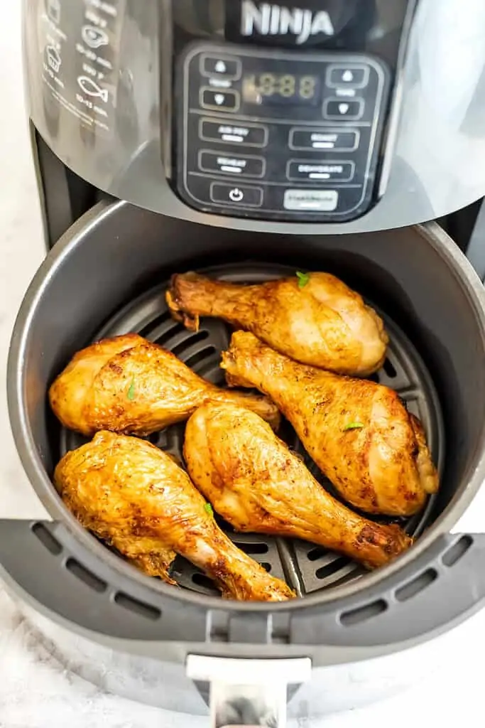 Air fryer filled with crispy chicken drumsticks.