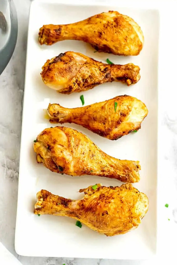 Chicken drumsticks on a white plate.