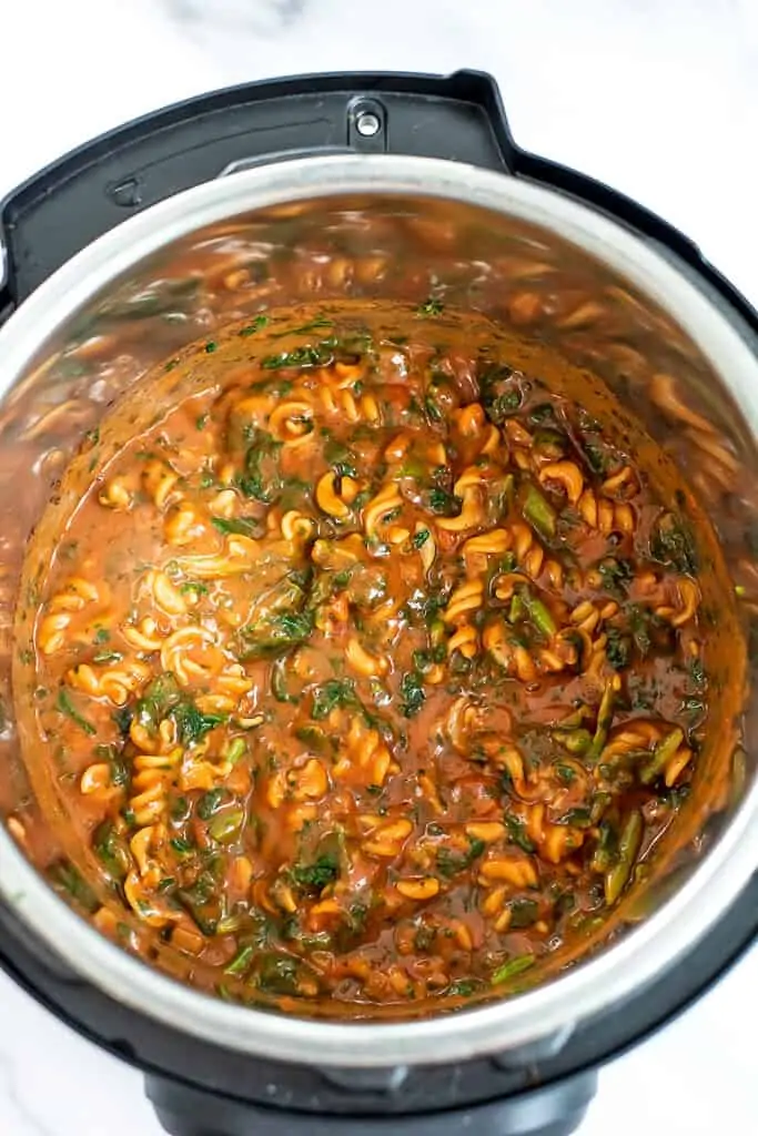 instant pot filled with chickpea pasta, marinara and spinach.