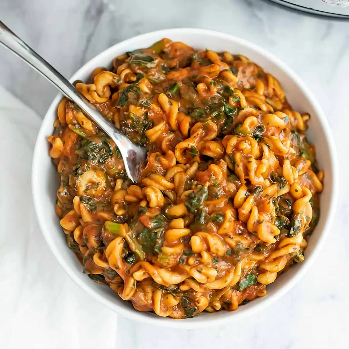 Fork in a bowl filled with marinara and chickpea pasta.