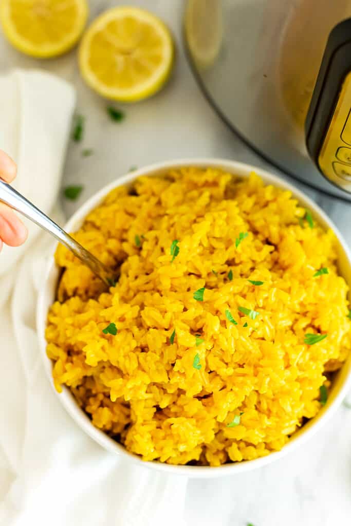 Large bowl of yellow rice with a spoon in the bowl.