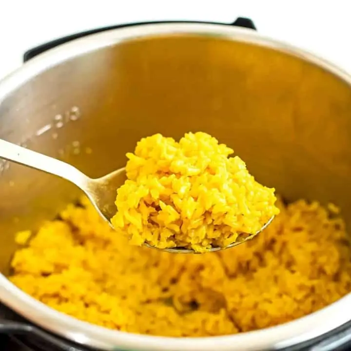 Large silver spoon holding a scoop of yellow rice.