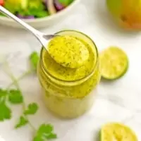 Spoon in a jar of mango dressing.