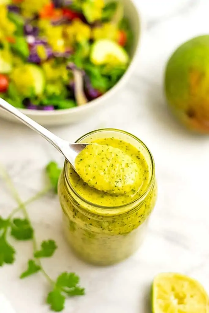 Spoonful of mango dressing out of the bottle.