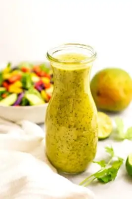 Large glass bottle filled with mango salad dressing.