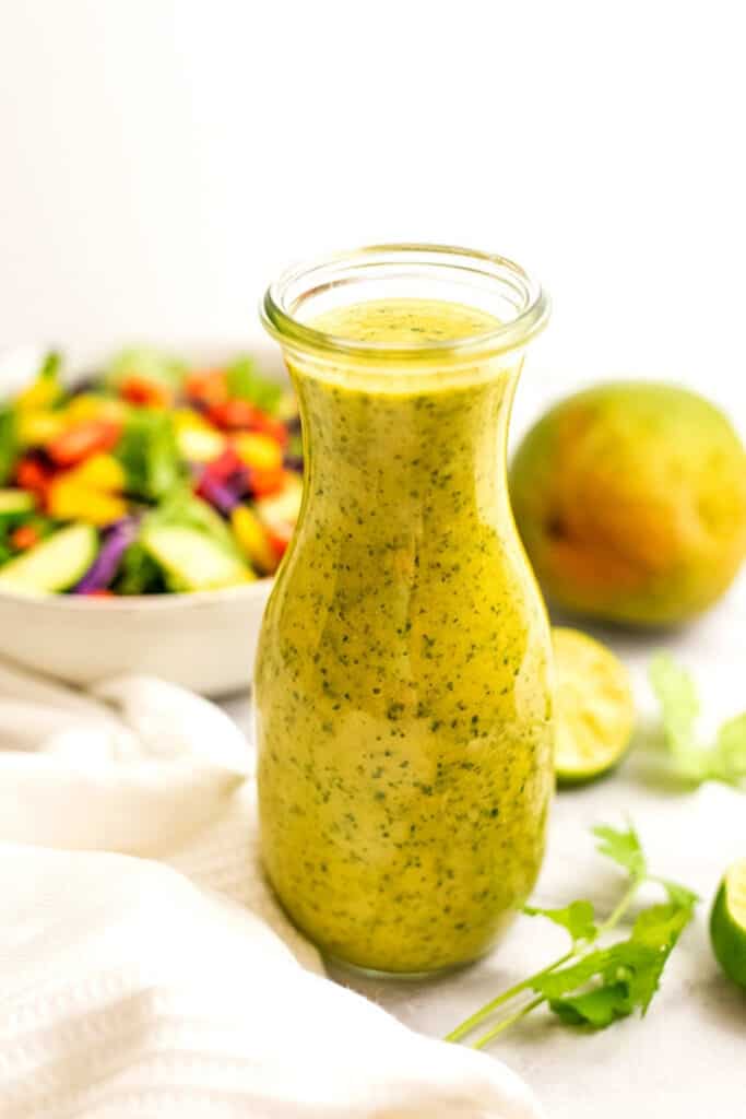 Large glass bottle filled with mango salad dressing.