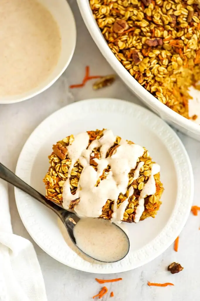 Spoonful of frosting on the plate next to a piece of oatmeal bake.