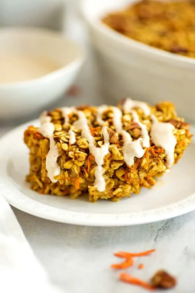 Baked carrot cake oatmeal on a plate with maple frosting drizzle.