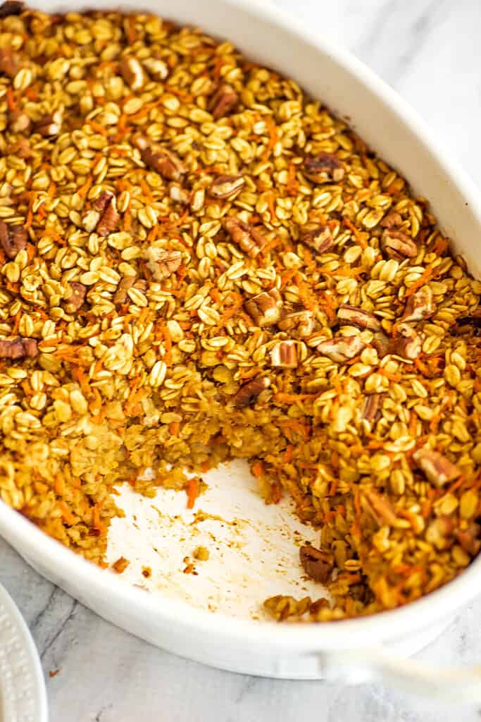 Baking pan full of baked carrot cake oatmeal with a piece removed.