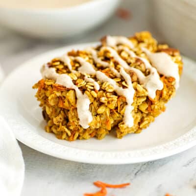 Oatmeal carrot cake with frosting on a white plate.