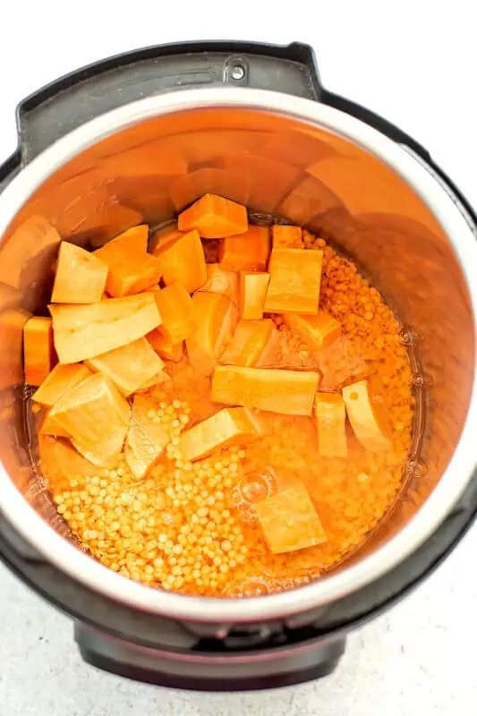 Cubed sweet potatoes and lentils in instant pot before coking.