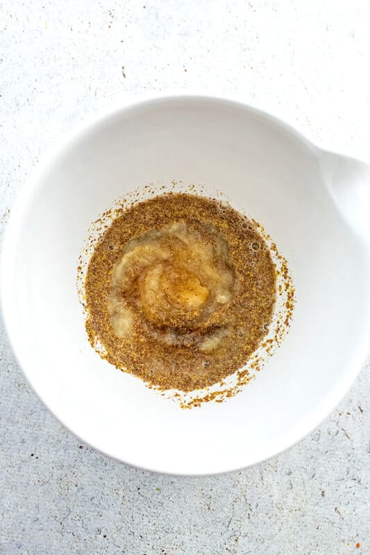 Ground flax and water in a large white bowl.