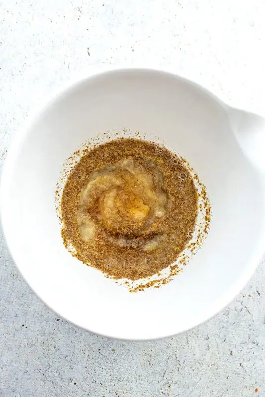 Ground flax and water in a large white bowl.