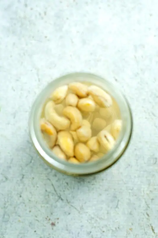 Glass jar with cashews soaking in water.