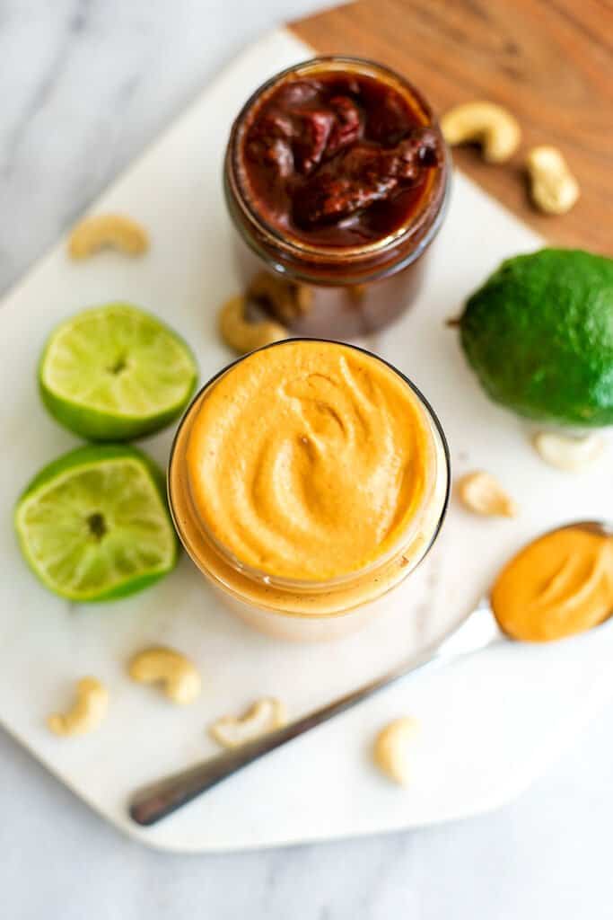 Chipotle mayo in a jar with limes and chipotle peppers.