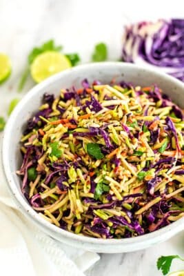 Asian Broccoli Slaw with limes and cabbage in background.
