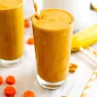 Carrot cake smoothie in a glass with orange straw.