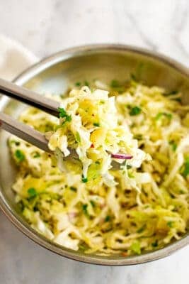 Serving of pineapple slaw being scooped from a bowl.