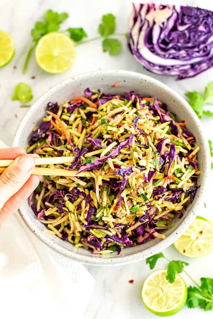 Chop sticks in a bowl of asian broccoli slaw.