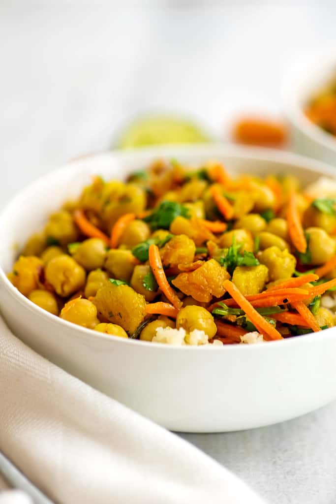 Bowl of apricot chickpea curry with white napkin.