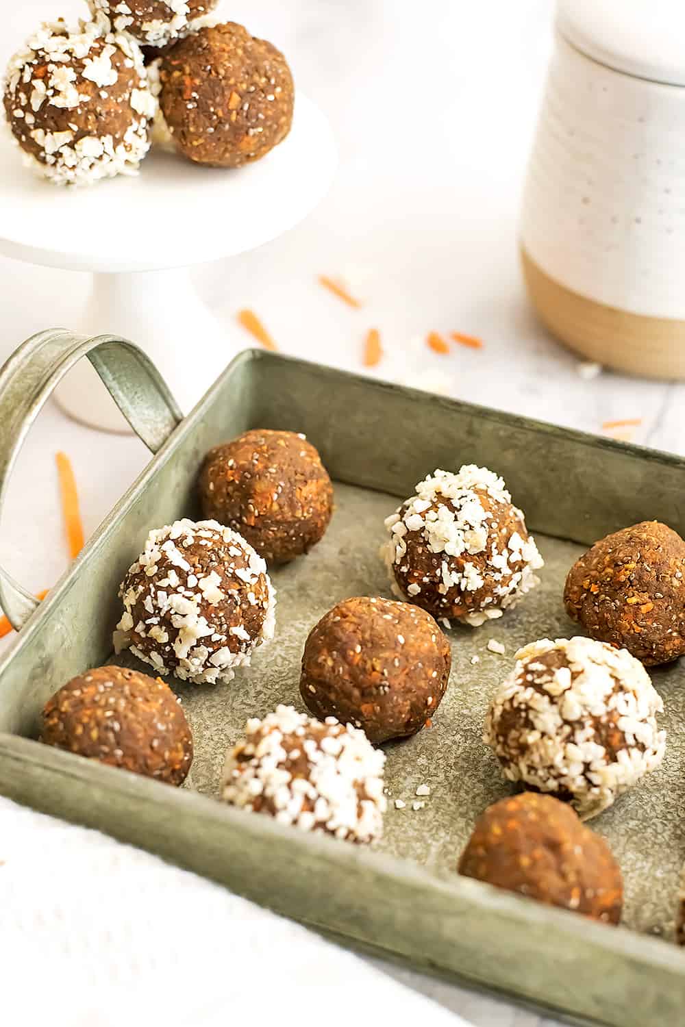 Carrot cake protein balls in a green tray with more in background.