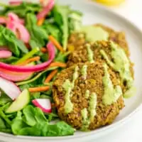 Plate of salad and 3 lentil falafel with green tahini drizzle.