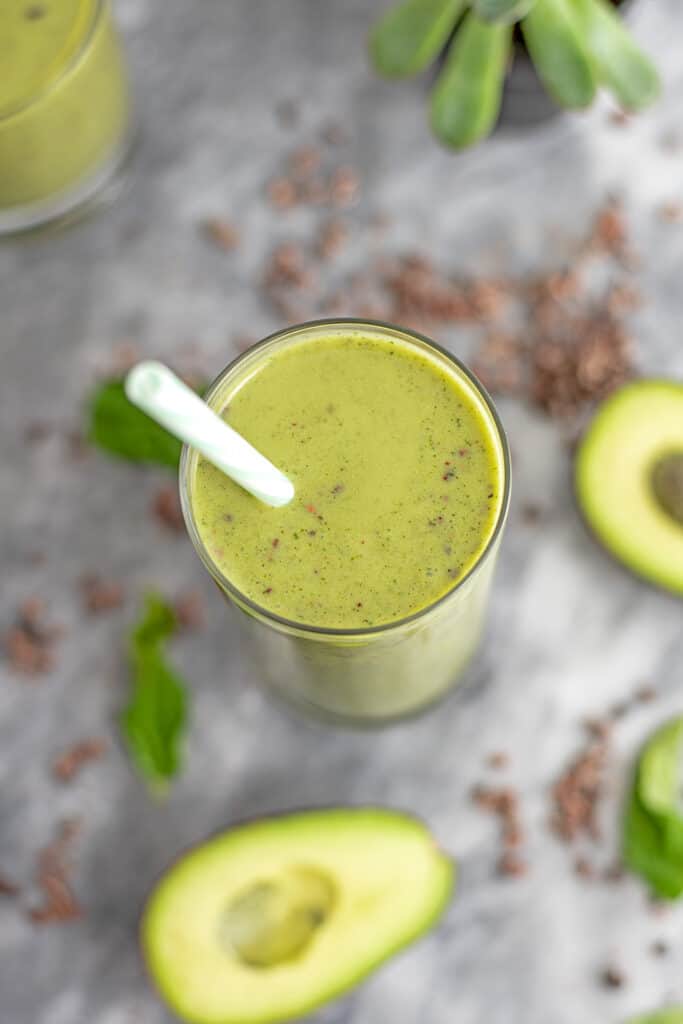 Avocado mint protein shake with a straw in the glass.