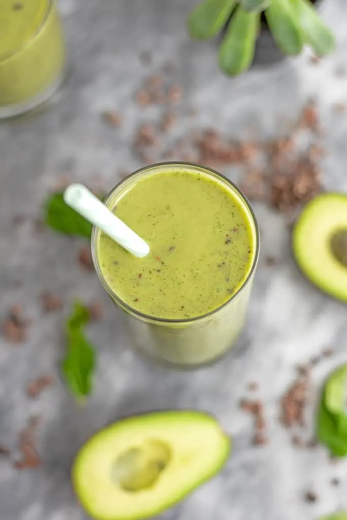 Avocado mint protein shake with a straw in the glass.