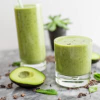 Mint avocado protein shake in a glass with avocado next to the glass.