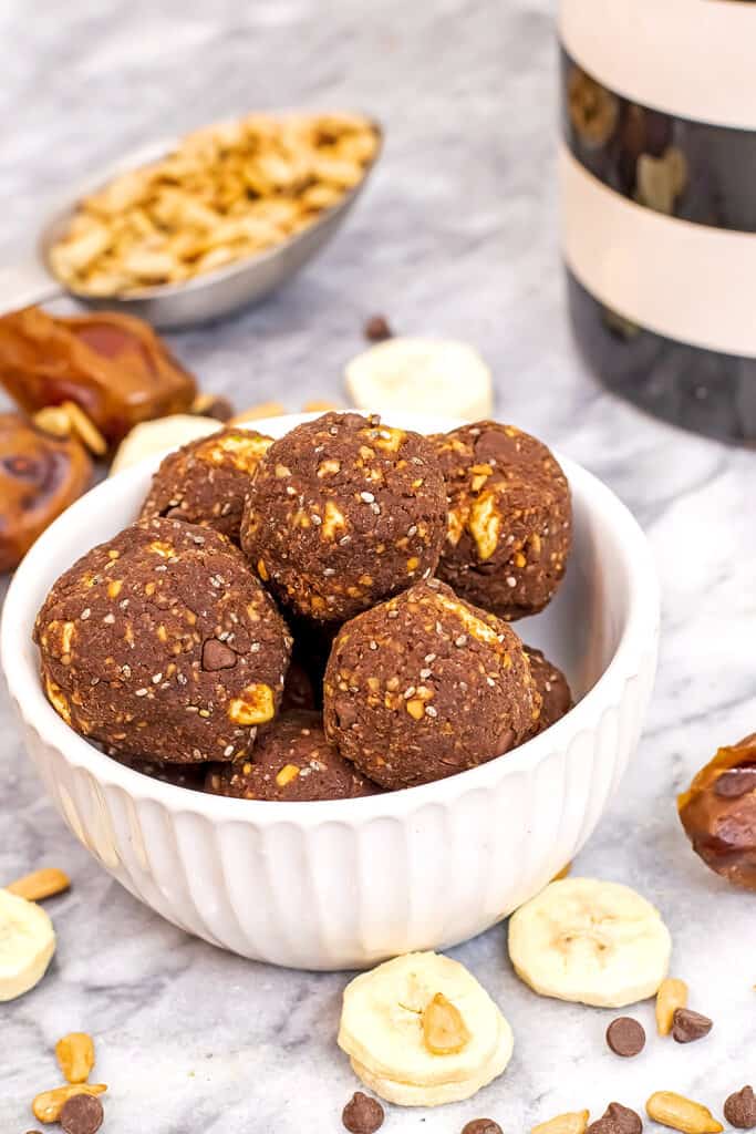 bowl filled with chocolate banana protein balls with dried bananas around bowl.