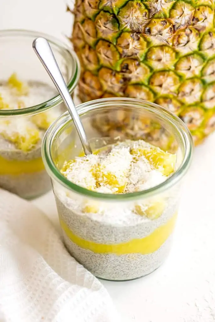 Pineapple mango chia pudding in a glass jar with pineapple in background.