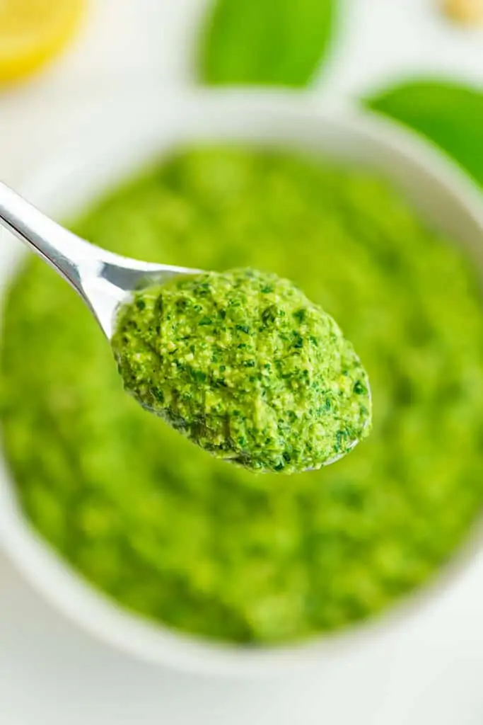 Spoonful of pesto over a bowl.