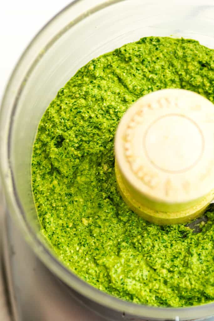 Food processor filled with vegan arugula pesto.