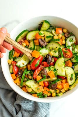 Wooden spoon in a bowl of Mediterranean Chopped Salad.