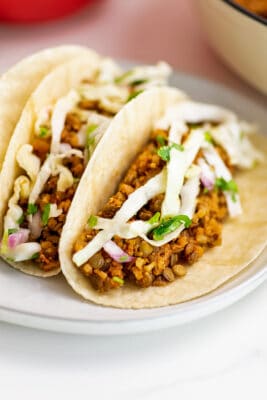 Cauliflower lentil tacos on a plate with slaw on top.