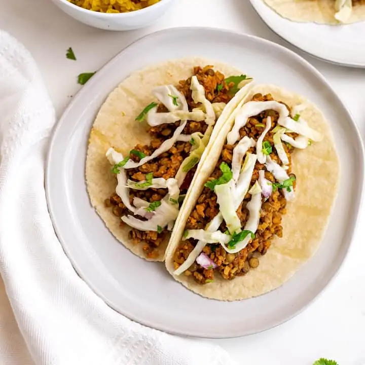 Two cauliflower lentil tacos on a plate.