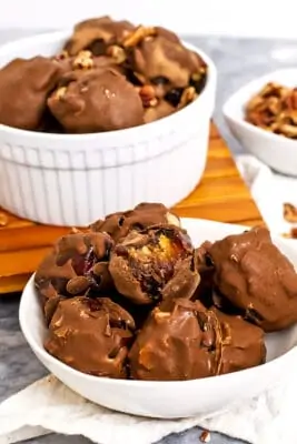 Bite taken out of a chocolate covered date in a bowl.