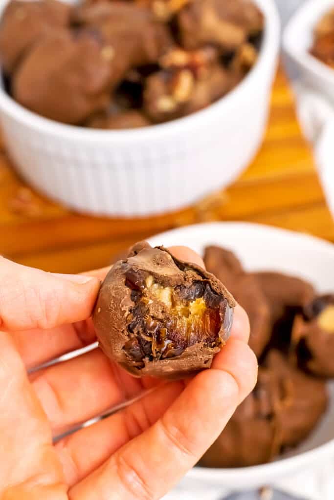 Hand holding peanut butter stuffed date with bite taken.