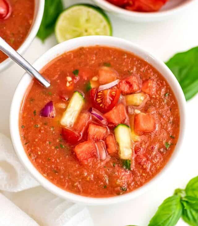 Watermelon gazpacho in white bowl with a spoon in the bowl.