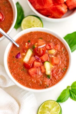 Watermelon gazpacho in white bowl with a spoon in the bowl.