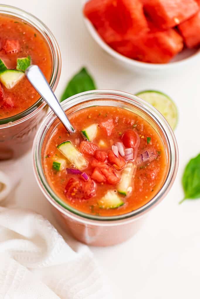 Watermelon gazpacho in a glass jar with a spoon.